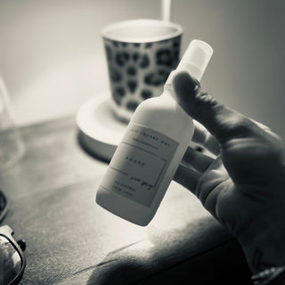 Hand spraying Amore Room Spray above a tidy desk.