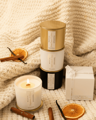 Candles stacked on a creamy blanket with orange slices and cinnamon sticks around.