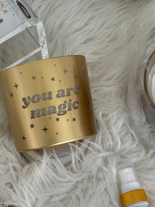Gold candle 'you are magic' text on a fluffy white surface