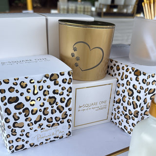 Decorative items including a candle, box, and bottle with leopard print design on a reflective surface.