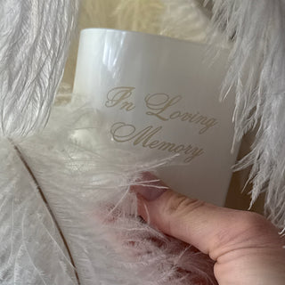 Hand holding a white candle with text on a textured white surface