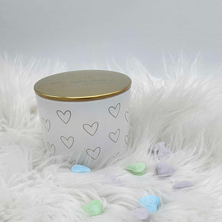 White ceramic jar with gold lid on a fluffy white surface