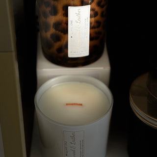 Two candles on a shelf with leopard print and white labels.