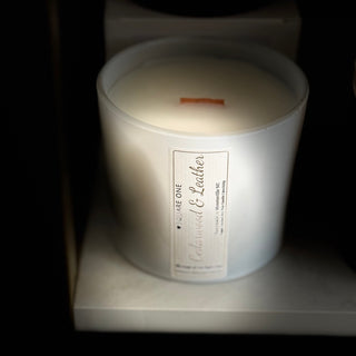 Candle in a white container with a label on a dark background