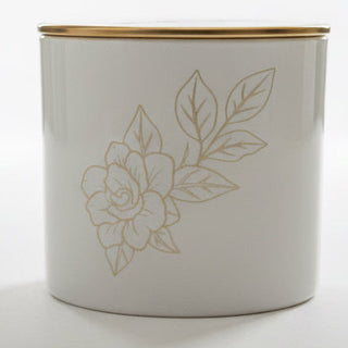 White container with floral design and gold lid on a white surface
