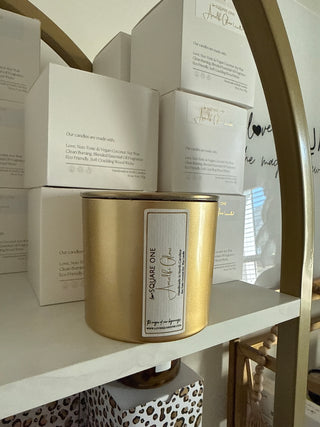 Gold cylindrical candle jar with a label on top of a marble shelf