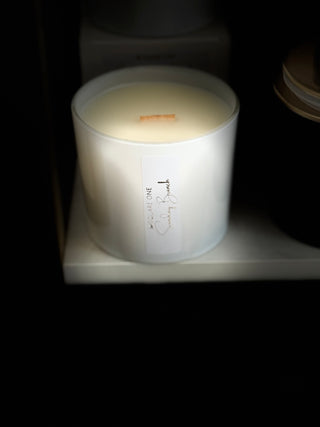 White candle in a container with a label on a dark background
