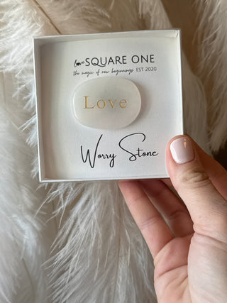 Hand holding a box with 'Square One' and 'Wavy Stone' branding on a fluffy white surface.