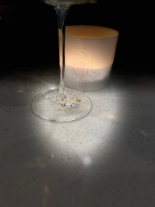 Wine glass with gold ring around base and a lit white candle 