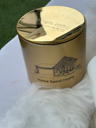 Gold-topped candle with black text and illustration on a white faux fur surface