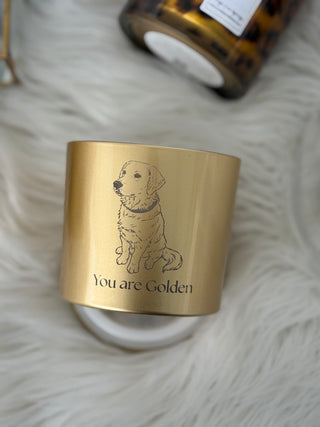 Gold candle jar with a dog illustration and 'You are Golden' text on a soft white surface.