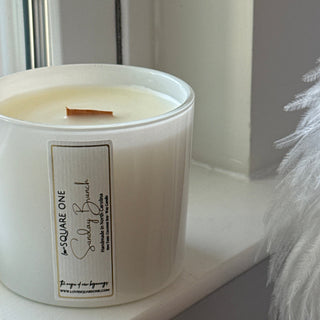 White cylindrical container candle with a label on a white surface