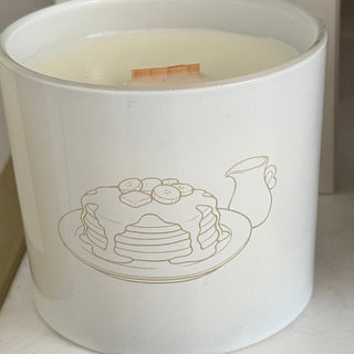 White container with a design of pancakes and a teapot on a white surface.