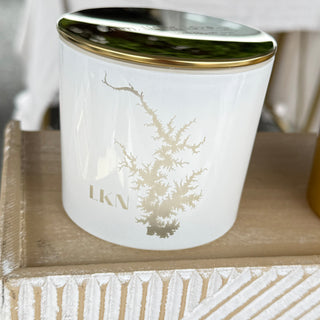 White candle holder with gold rim and engraved design on a wooden surface