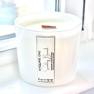 White candle with a label with gold text on a white surface