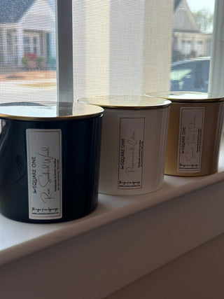 Three love square one candles in a window SIL next to a white feather curtain 