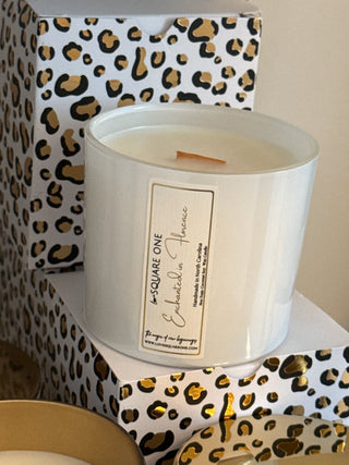 White candle in a decorative container with a leopard print pattern on a beige background