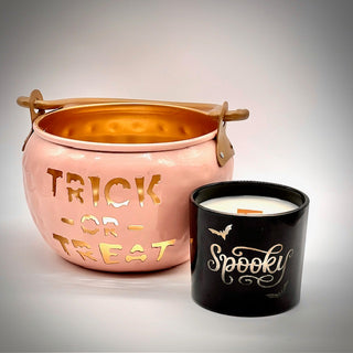 Pink ceramic container with 'Trick or Treat' text and black candle with 'Spooky' text on a gray background