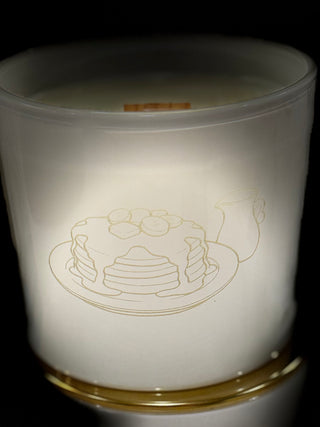 White candle with a design of pancakes on a black background