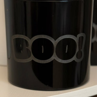 BOO candle on white shelf