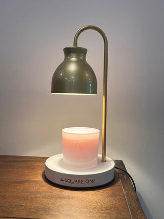 Lit birthday candle showing glowing etched cake design, surrounded by birthday decor and a candle warmer