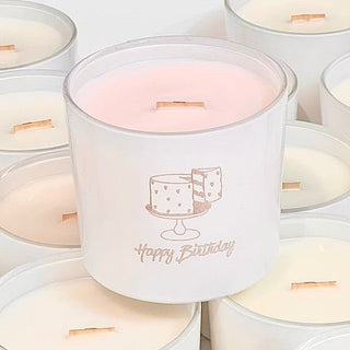 White candle with Happy Birthday cake design etched in glass, sitting in a gift box on a table