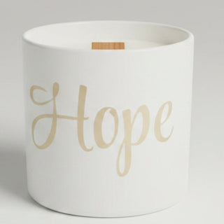 A collection of candles in white containers and boxes, including one with a leopard print pattern and one featuring the word 'Hope' in gold script.
