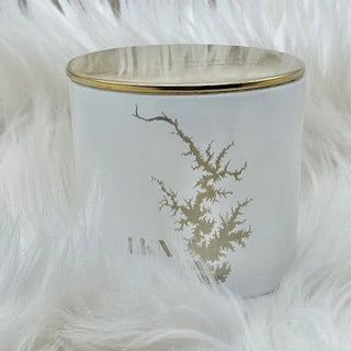 White candle holder with gold rim and leaf design on a fluffy white background