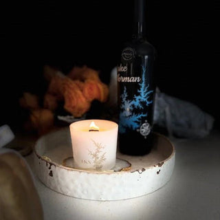 Candle and bottle on a white tray with a dark background
