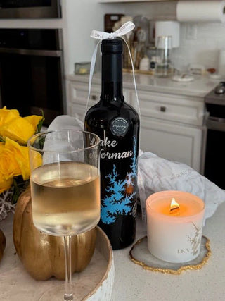 Bottle of Lake of the Woods wine with a glass of wine and a candle on a kitchen counter.