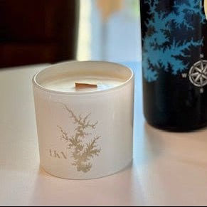 Candle with decorative design and a dark container with blue design on a light surface