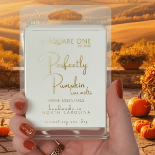 Perfectly Pumpkin Wax melt being held in hands by a red manicured lady with a fall background