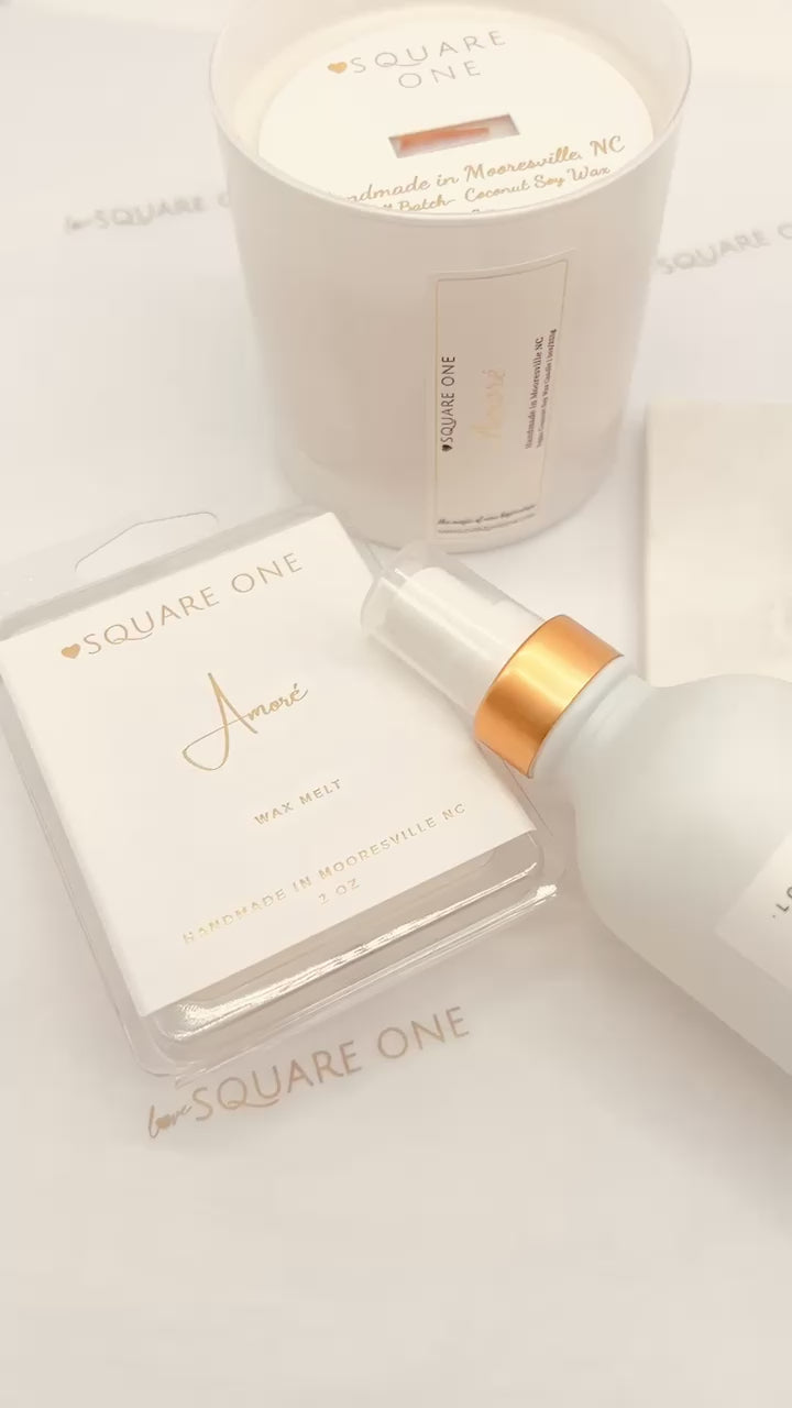 A square clamshell package containing six wax melt cubes labeled “Amoré,” featuring a soft, romantic design with clean branding.